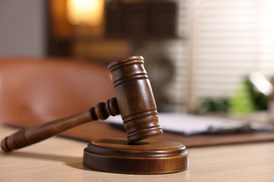 Photo of Judge's gavel on wooden table in office, closeup. Space for text