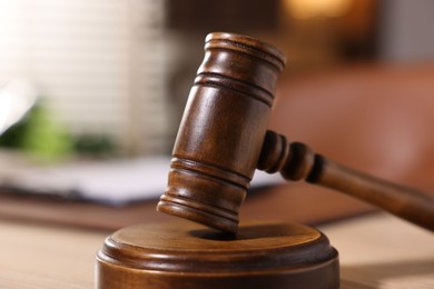 Photo of Judge's gavel on wooden table in office, closeup