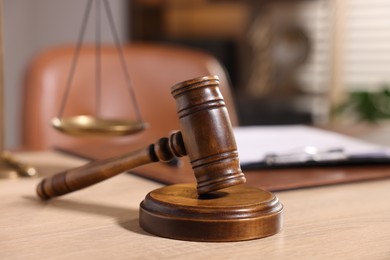 Photo of Judge's gavel on wooden table in office, closeup