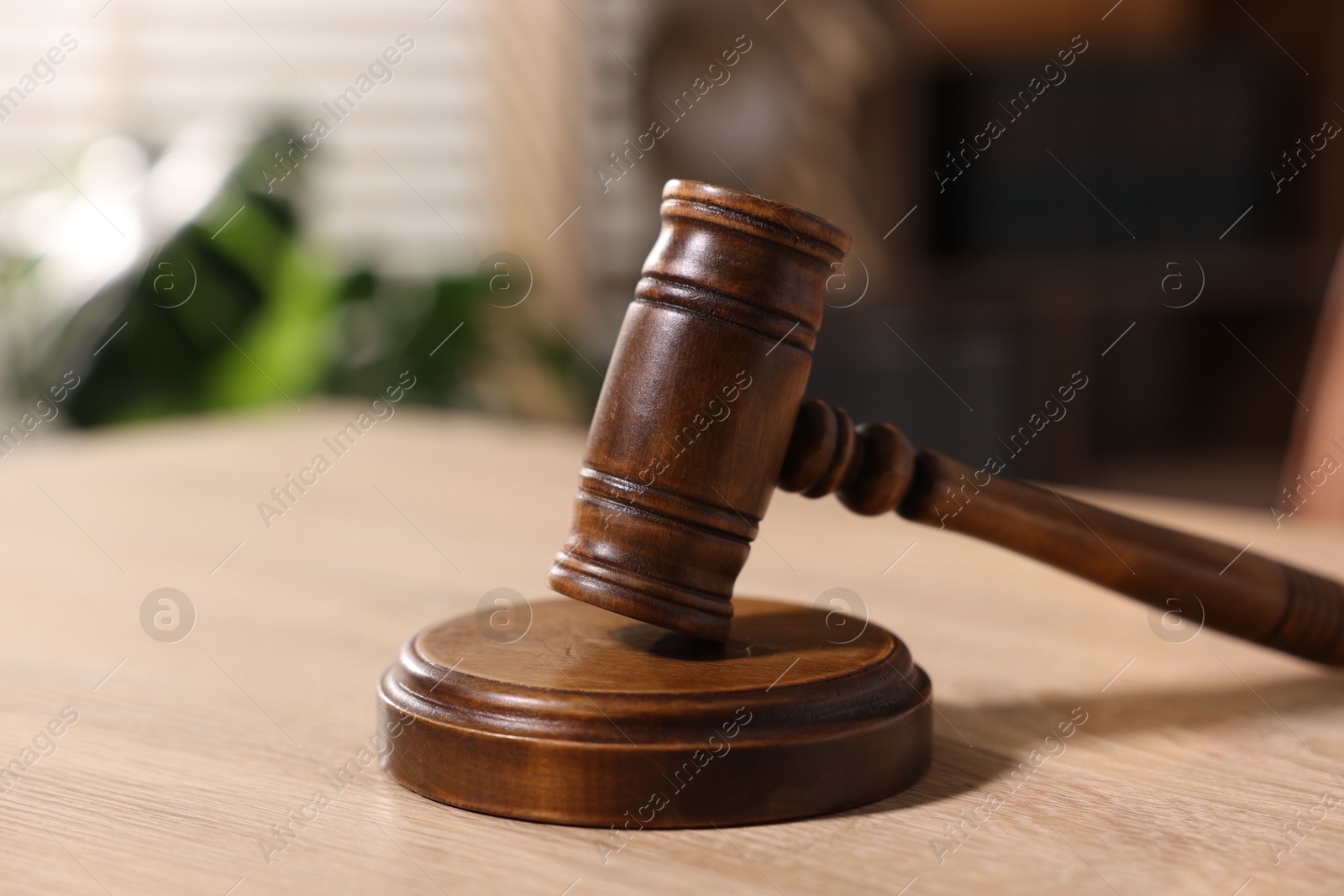 Photo of Judge's gavel on wooden table in office, closeup