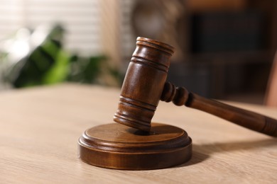 Photo of Judge's gavel on wooden table in office, closeup