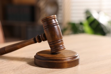 Photo of Judge's gavel on wooden table in office, closeup