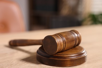 Photo of Judge's gavel on wooden table in office, closeup