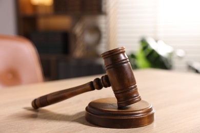 Photo of Judge's gavel on wooden table in office, closeup