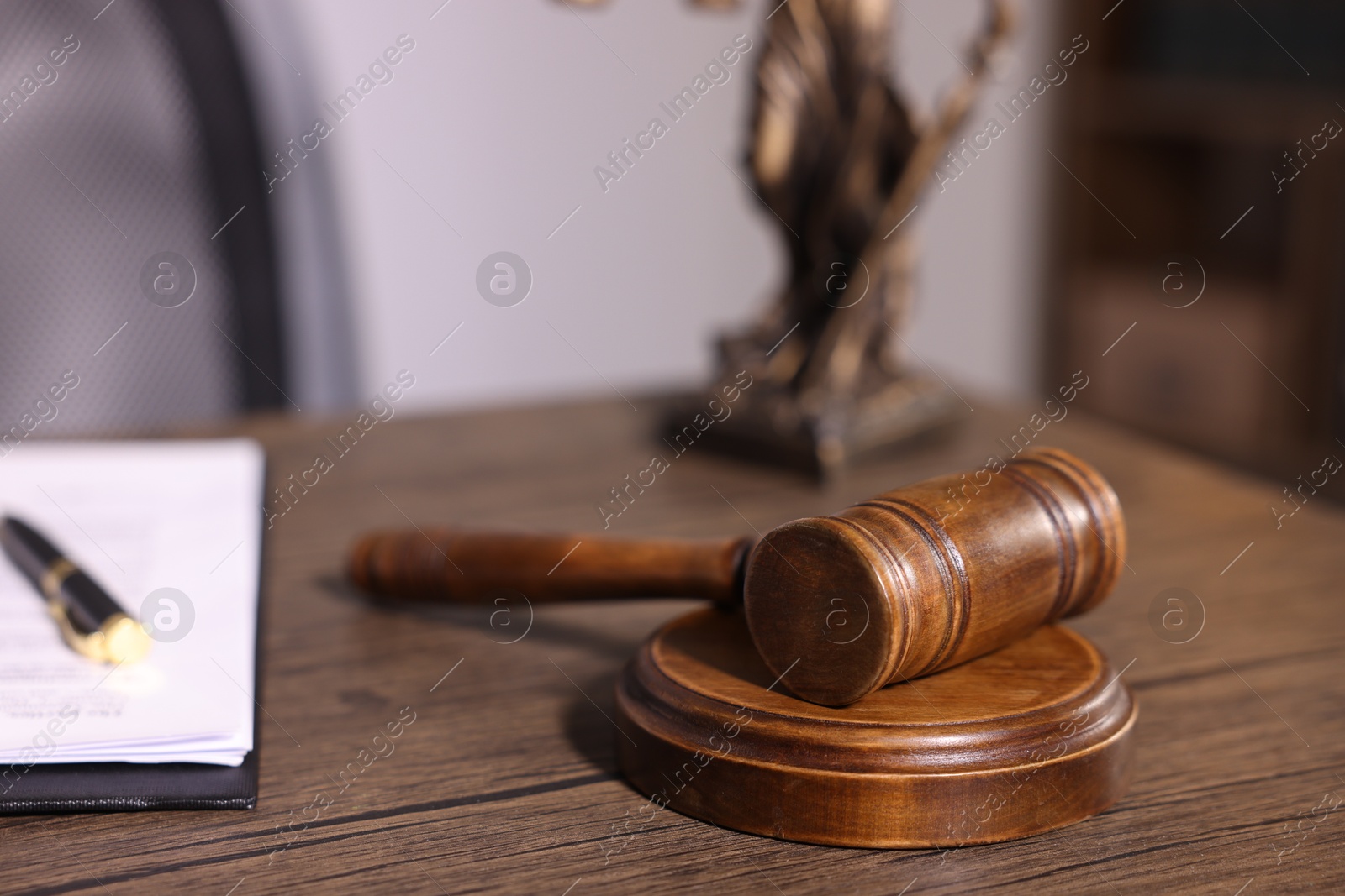 Photo of Judge's gavel on wooden table in office, closeup