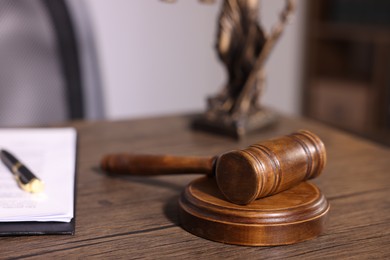 Photo of Judge's gavel on wooden table in office, closeup