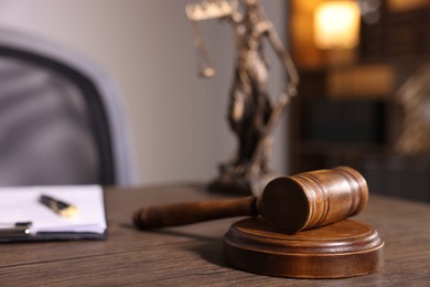 Photo of Judge's gavel on wooden table in office, closeup