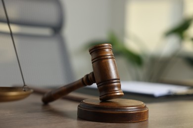 Photo of Judge's gavel on wooden table in office, closeup