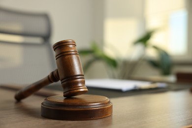Photo of Judge's gavel on wooden table in office, closeup. Space for text