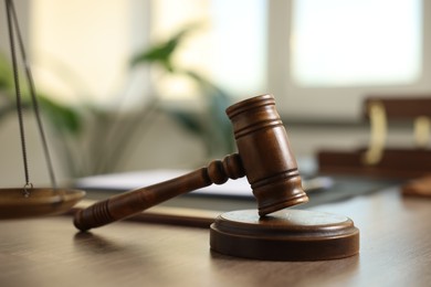 Photo of Judge's gavel on wooden table in office, closeup
