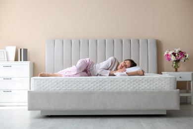 Photo of Woman sleeping on bed with orthopedic mattress at home