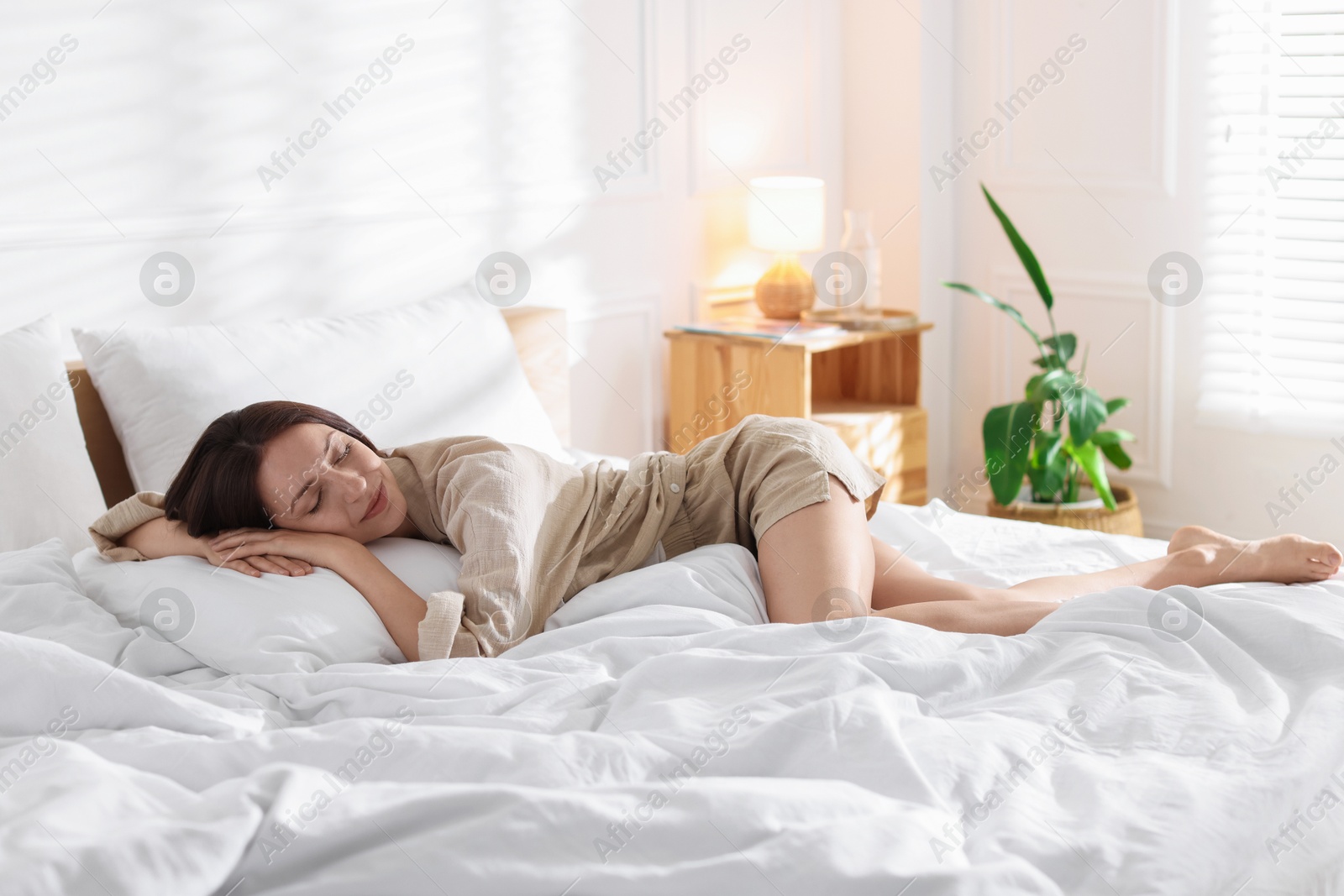 Woman lying on bed with soft mattress at home. Space for text Photo of Woman lying on bed with soft mattress at home. Space for text