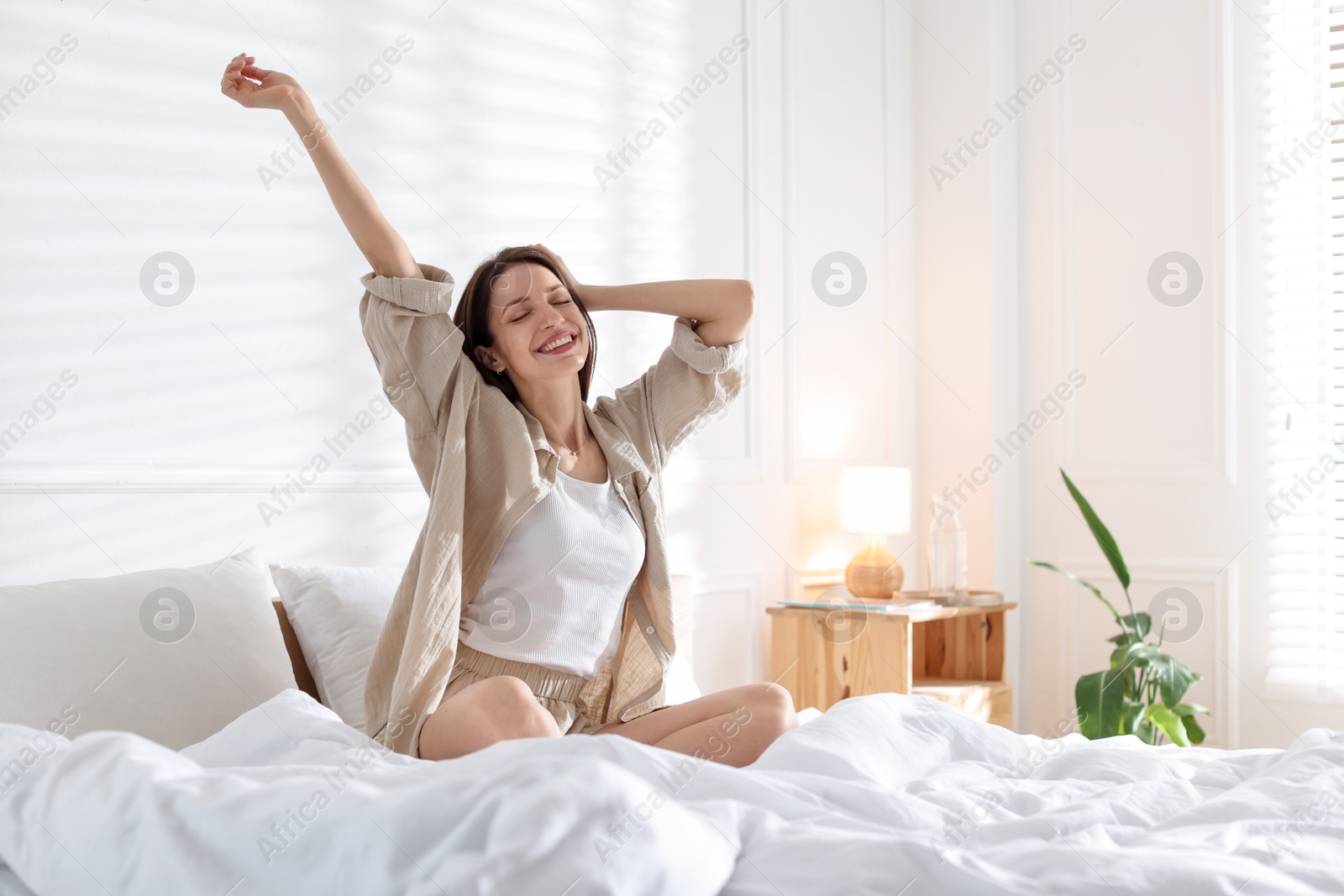 Woman stretching on bed with soft mattress at home. Space for text Photo of Woman stretching on bed with soft mattress at home. Space for text