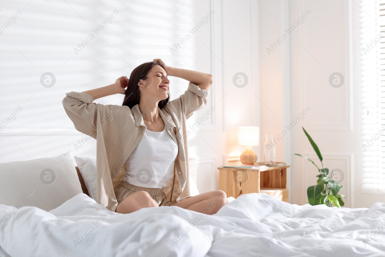 Woman stretching on bed with soft mattress at home. Space for text Photo of Woman stretching on bed with soft mattress at home. Space for text