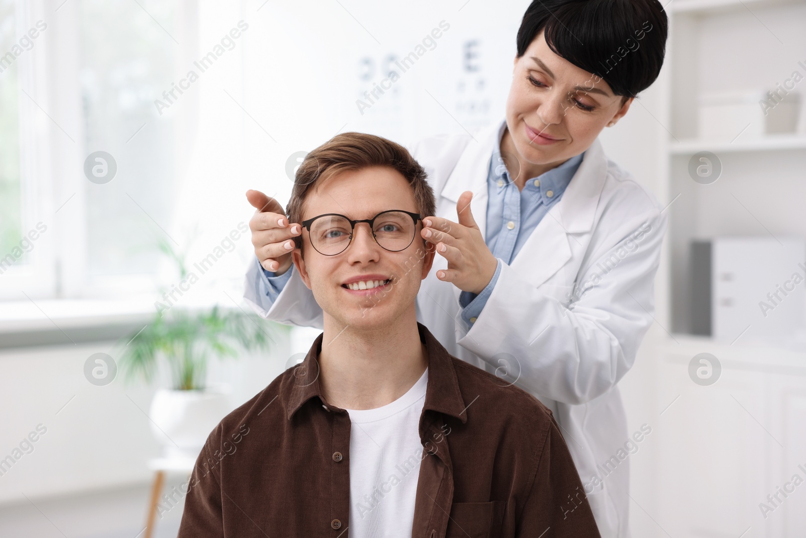 Photo of Ophthalmologist giving glasses to patient in clinic