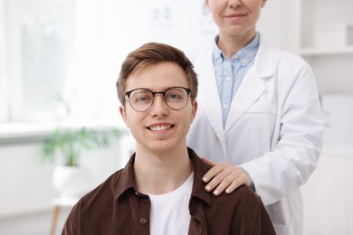 Photo of Professional ophthalmologist and patient with glasses in clinic, closeup