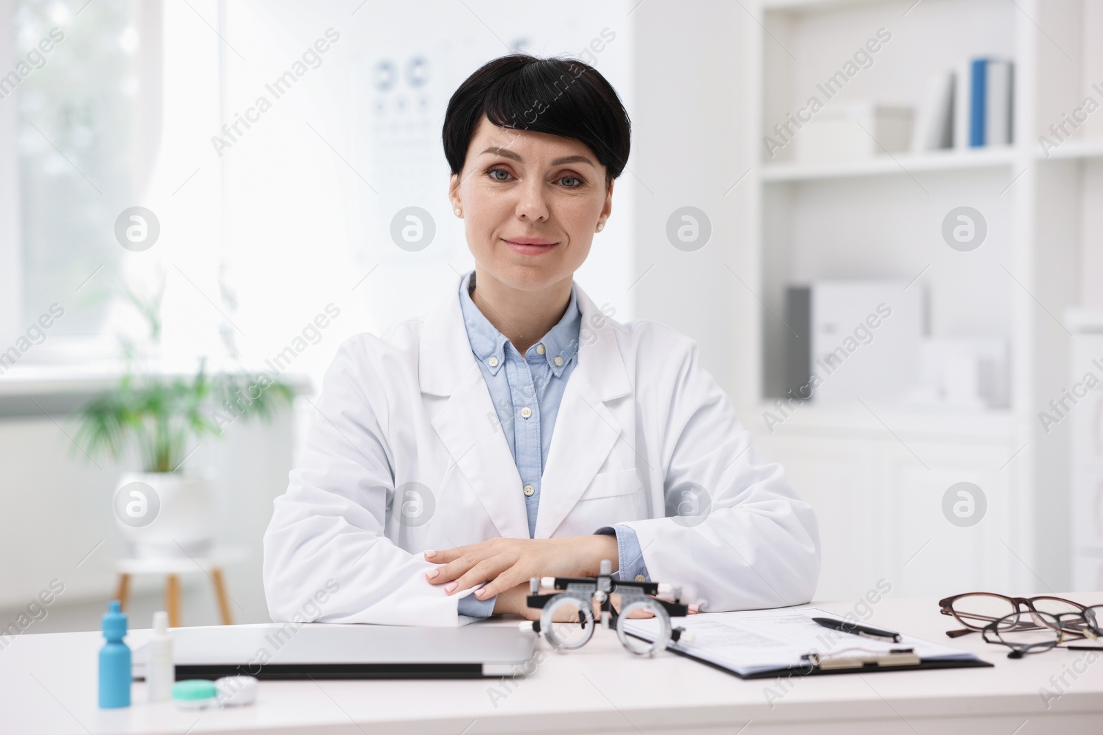 Portrait of professional ophthalmologist at white table in clinic Photo of Portrait of professional ophthalmologist at white table in clinic