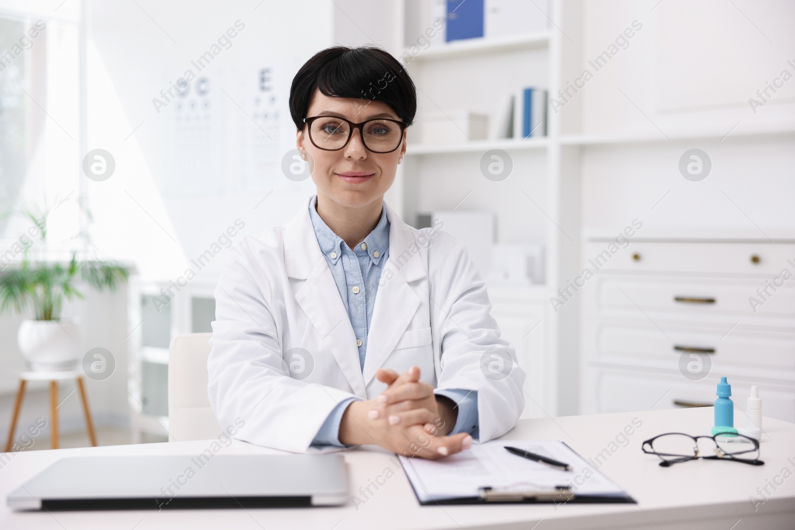 Portrait of professional ophthalmologist at white table in clinic Photo of Portrait of professional ophthalmologist at white table in clinic
