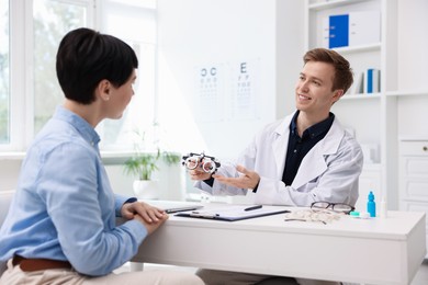 Photo of Ophthalmologist consulting woman at table in clinic