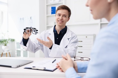 Photo of Ophthalmologist consulting woman at white table in clinic