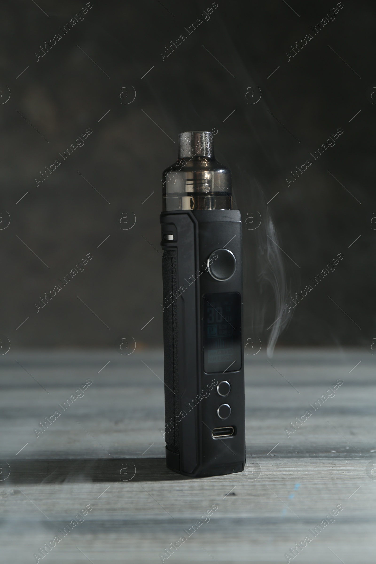 One electronic smoking device in smoke on wooden table against grey background, closeup Photo of One electronic smoking device in smoke on wooden table against grey background, closeup