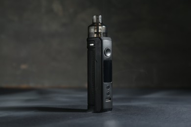Photo of One electronic smoking device on dark table against grey background, closeup