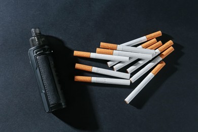 Photo of Electronic smoking device and cigarettes on dark table, flat lay