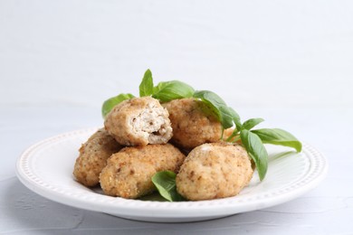 Photo of Tasty fried croquettes and basil on white textured table, closeup