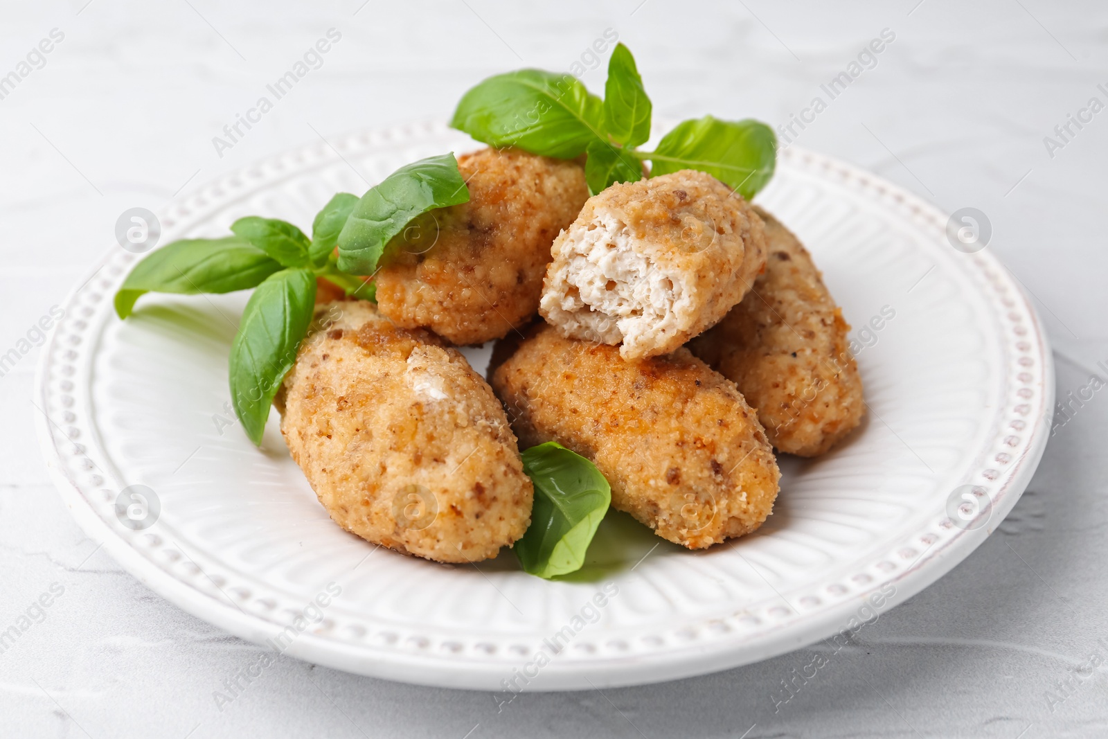 Tasty fried croquettes and basil on white textured table, closeup Photo of Tasty fried croquettes and basil on white textured table, closeup