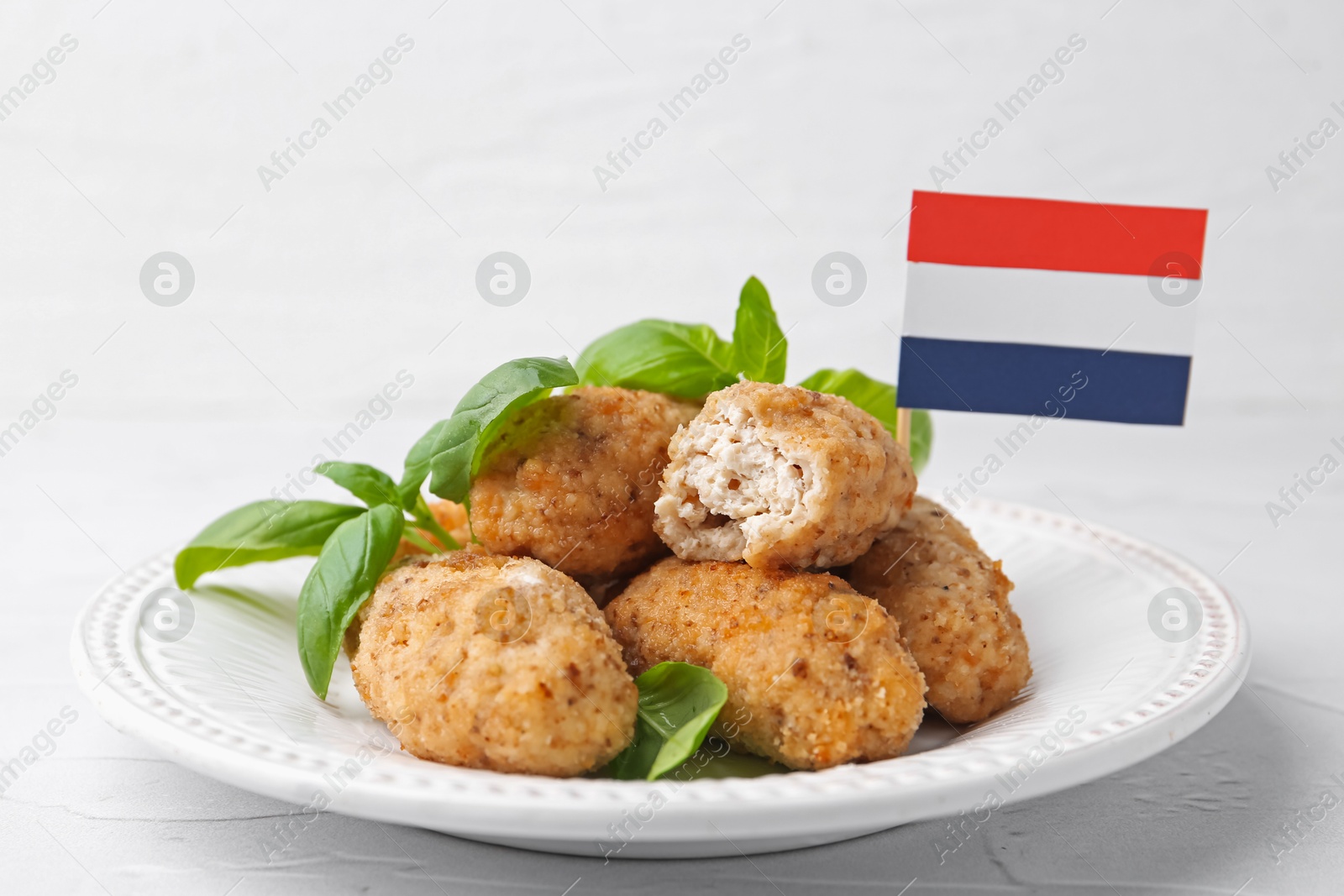 Tasty fried croquettes, basil and flag of Netherlands on white textured table, closeup Photo of Tasty fried croquettes, basil and flag of Netherlands on white textured table, closeup
