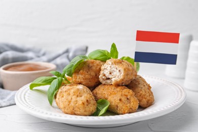 Photo of Tasty fried croquettes, basil, flag of Netherlands and sauce on white textured table, closeup