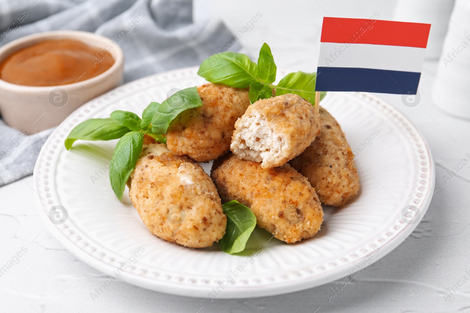 Tasty fried croquettes, basil, flag of Netherlands and sauce on white textured table, closeup Photo of Tasty fried croquettes, basil, flag of Netherlands and sauce on white textured table, closeup