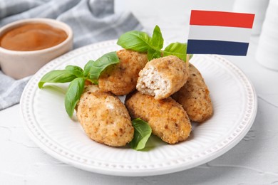 Photo of Tasty fried croquettes, basil, flag of Netherlands and sauce on white textured table, closeup
