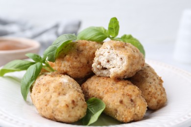 Photo of Tasty fried croquettes and basil on table, closeup