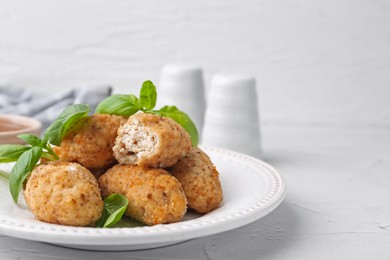 Photo of Tasty fried croquettes and basil on white textured table, closeup. Space for text