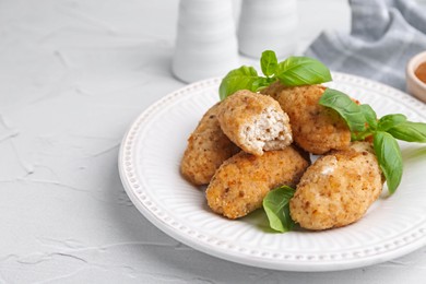 Photo of Tasty fried croquettes and basil on white textured table, closeup. Space for text