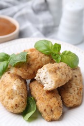 Photo of Tasty fried croquettes and basil on table, closeup