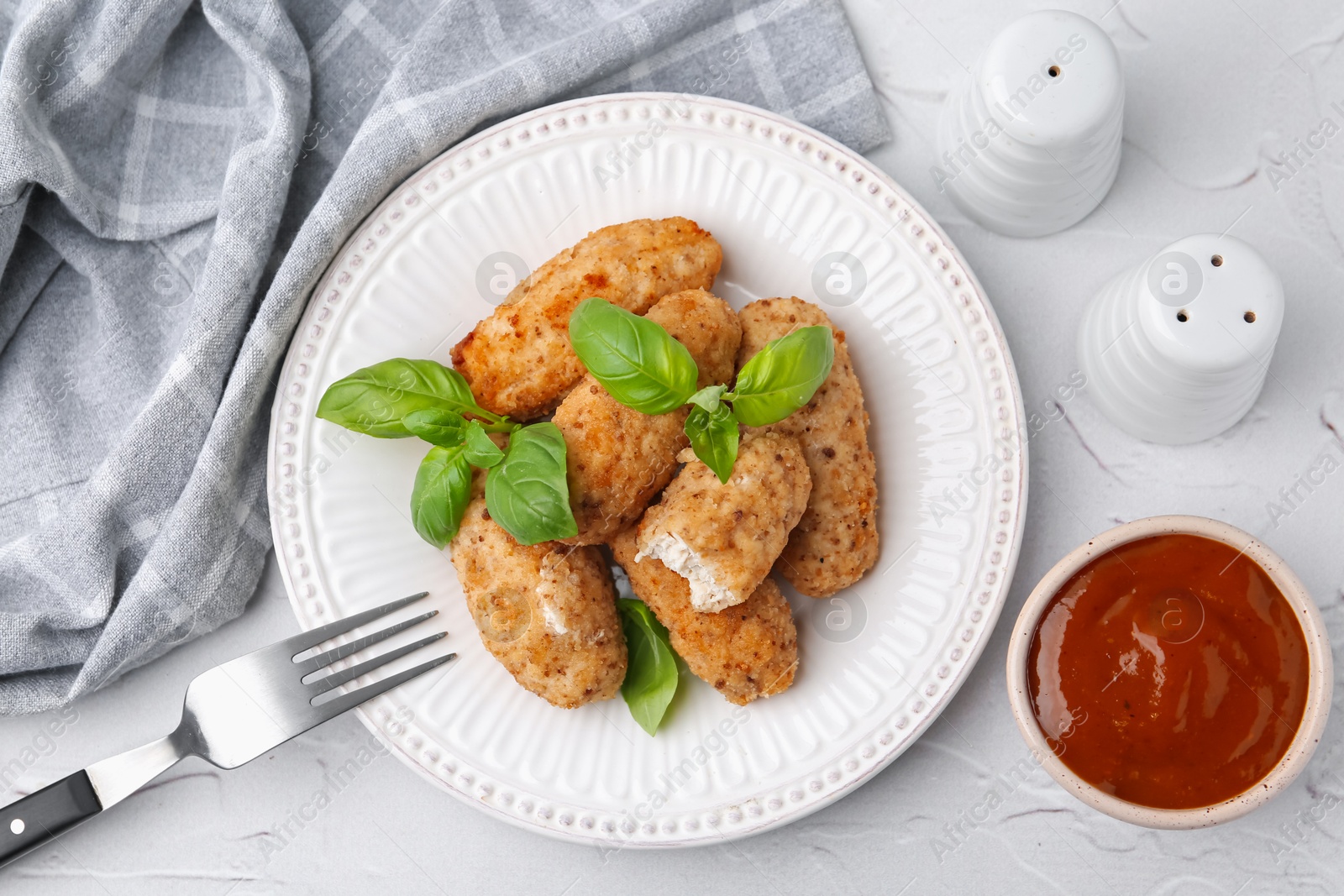 Tasty fried croquettes, basil and sauce on white textured table, flat lay Photo of Tasty fried croquettes, basil and sauce on white textured table, flat lay