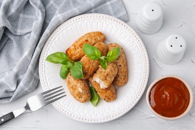 Photo of Tasty fried croquettes, basil and sauce on white textured table, flat lay