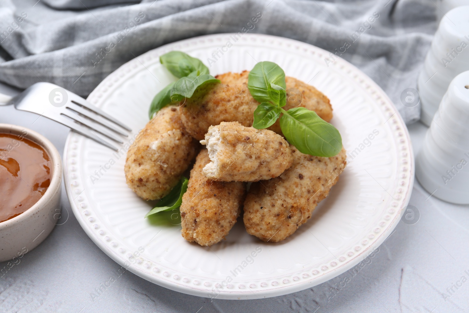 Tasty fried croquettes, basil and sauce on white textured table, closeup Photo of Tasty fried croquettes, basil and sauce on white textured table, closeup