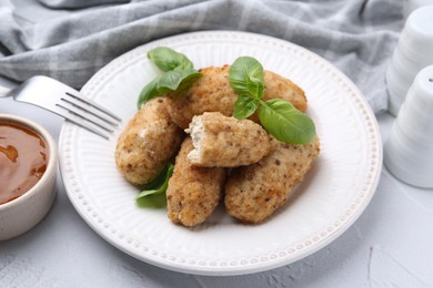 Photo of Tasty fried croquettes, basil and sauce on white textured table, closeup