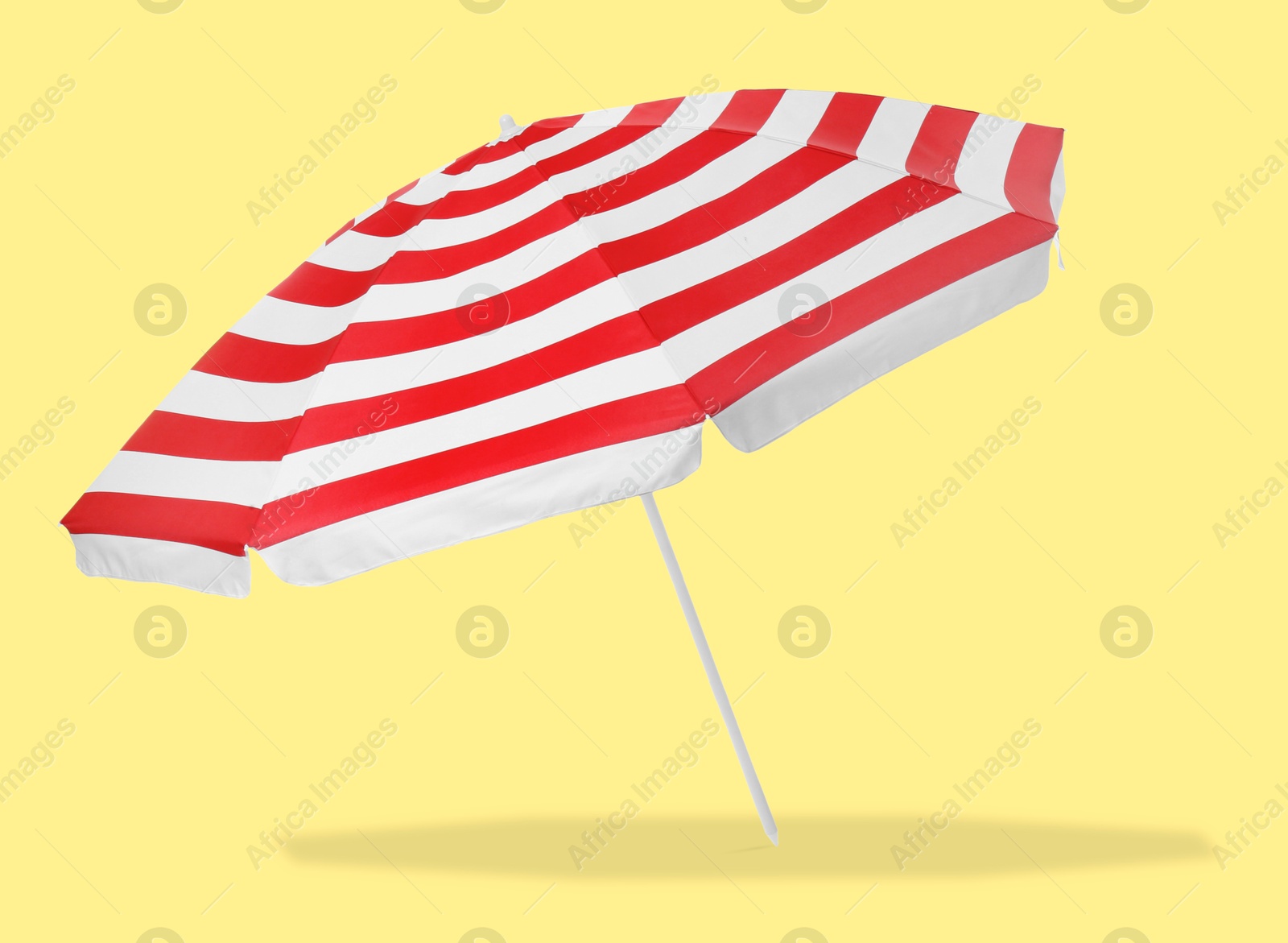 Red striped beach umbrella casting shadow on yellow background Image of Red striped beach umbrella casting shadow on yellow background