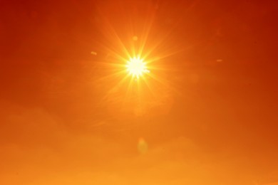 Image of Bright sun in orange sky during hot summer weather. Extremely high temperature