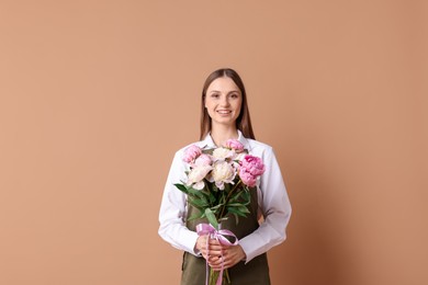 Photo of Florist with beautiful bouquet of peonies on dark beige background