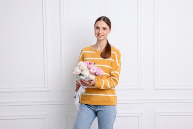 Photo of Woman with beautiful bouquet of peonies near white wall indoors