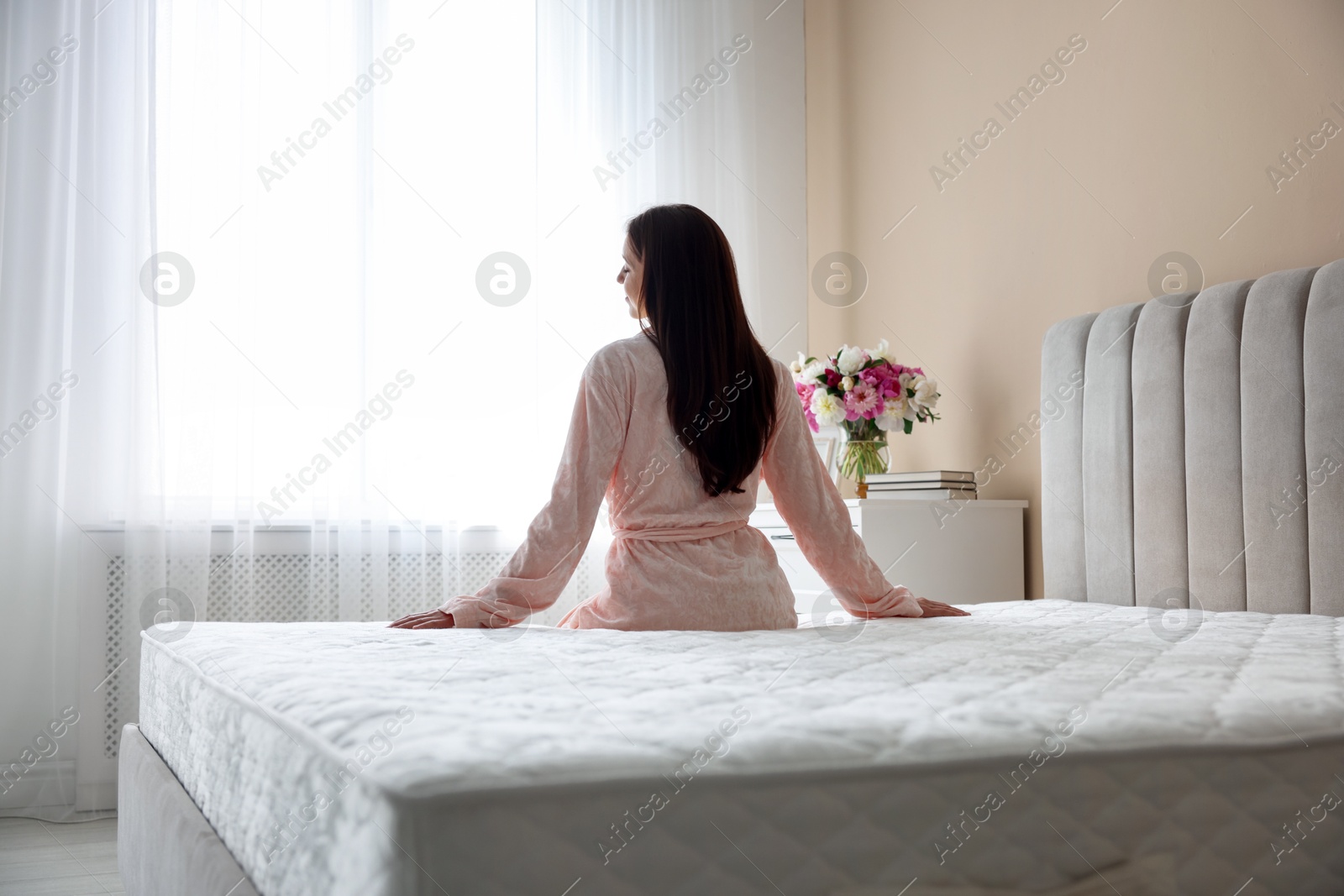 Photo of Woman on bed with orthopedic mattress at home, back view