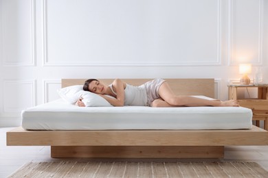 Photo of Woman sleeping on bed with orthopedic mattress at home
