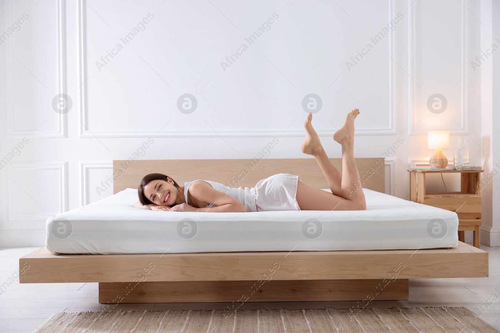 Photo of Woman lying on bed with orthopedic mattress at home