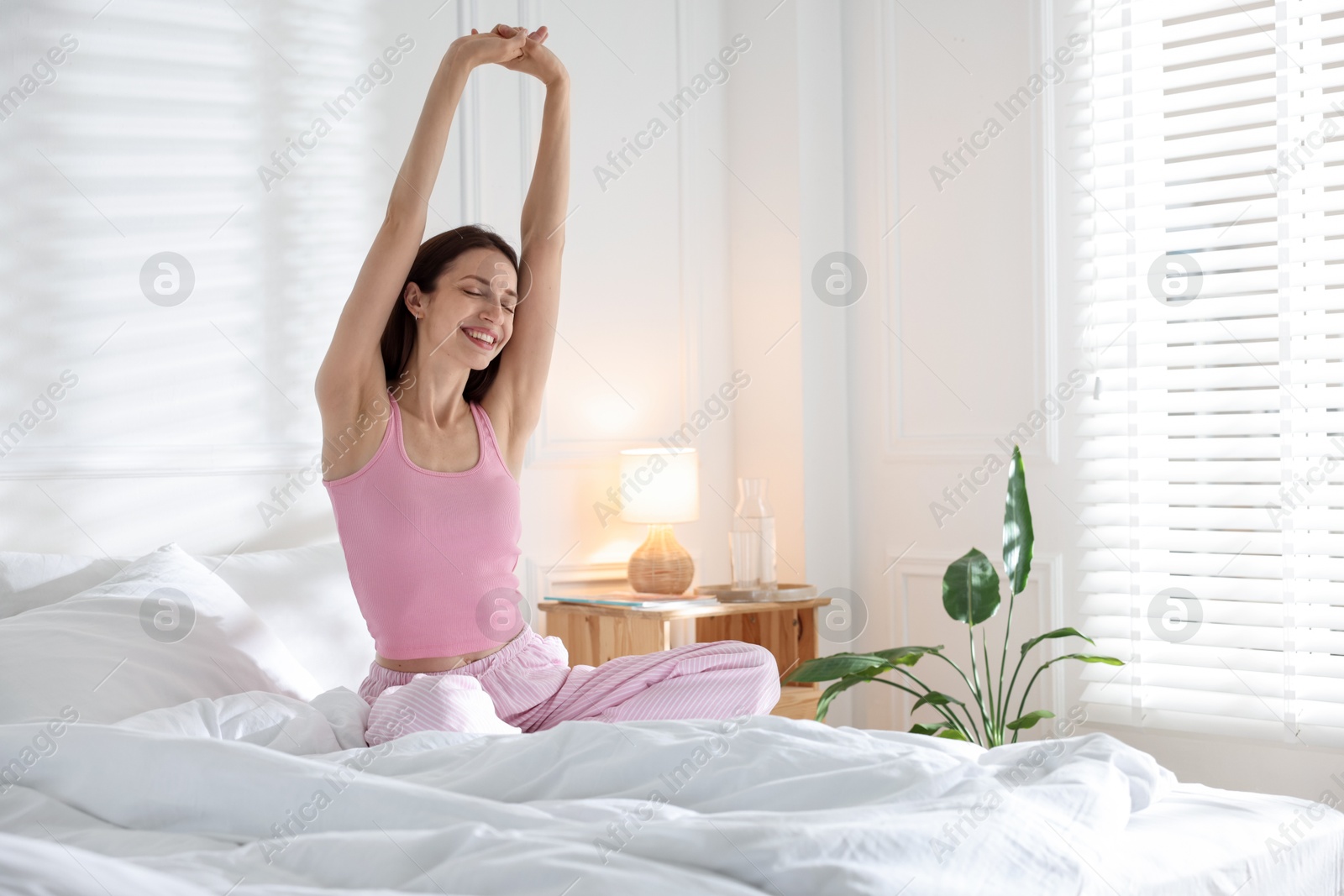 Woman stretching on bed with soft mattress at home. Space for text Photo of Woman stretching on bed with soft mattress at home. Space for text