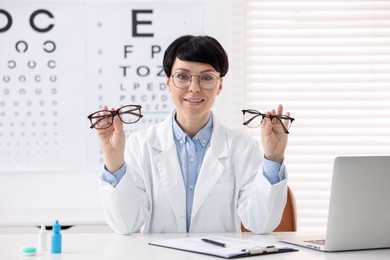 Photo of Portrait of professional ophthalmologist with glasses at white table in clinic
